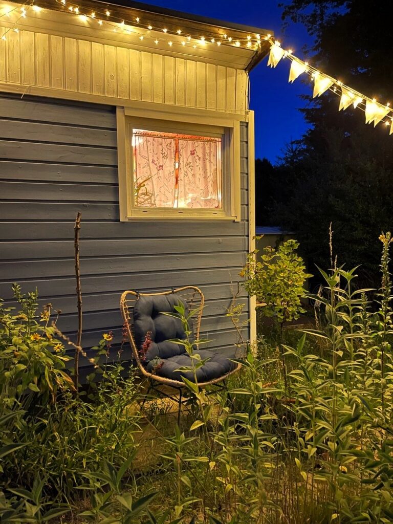 Rattansessel mit blauen wetterfesten Kissen als Sitzecke im Kleingarten