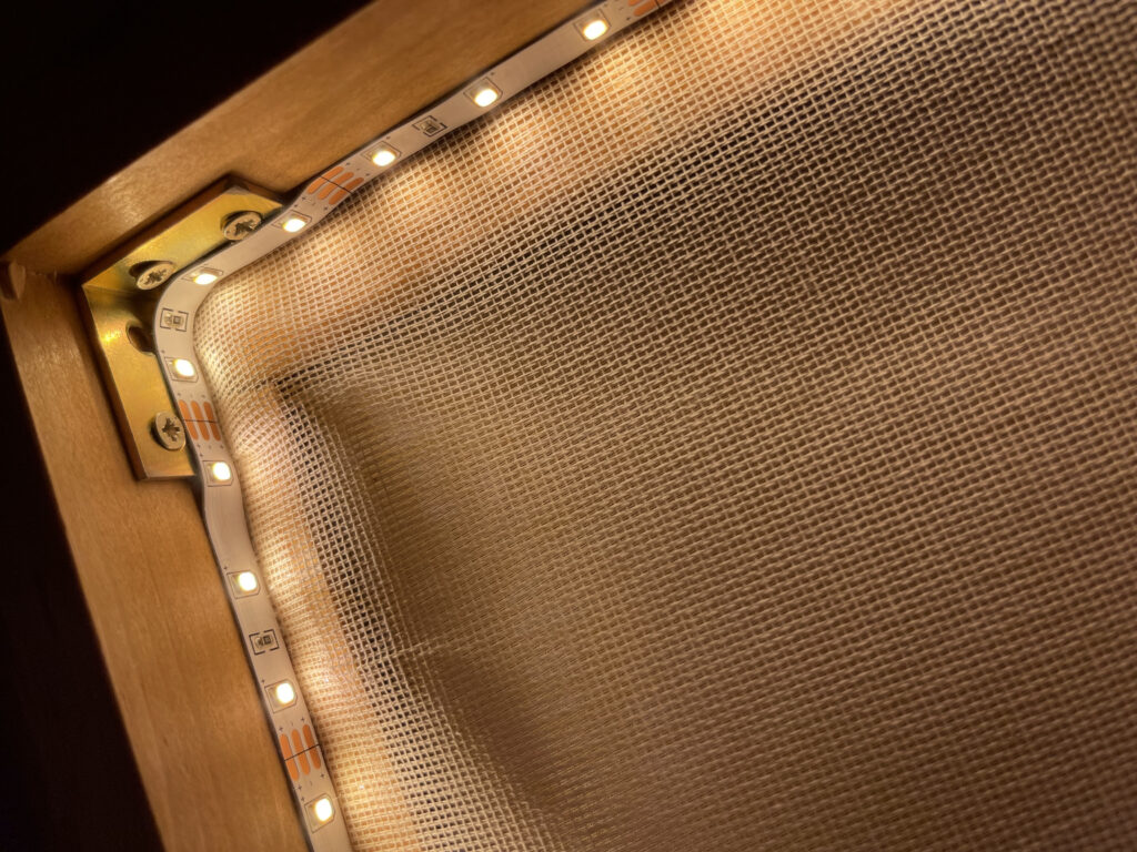 Konstruktionsdetail einer Wandlampe DIY - Eckverbindung des Holzrahmens mit Winkel und eingelassenem LED-Streifen.